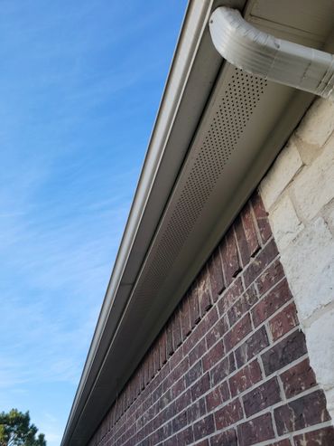 Close-up of a house's roofline with gutter and blue sky.
