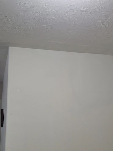 Plain white wall with textured ceiling above.