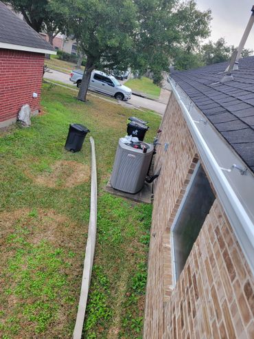 Residential backyard with air conditioning unit and trash bins.