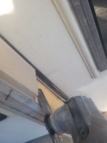A power tool scraping paint from a wooden surface near a door frame.