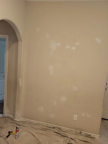 Wall being prepared for painting with patching and tools on the floor.