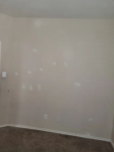Beige wall with white patches and carpeted floor.
