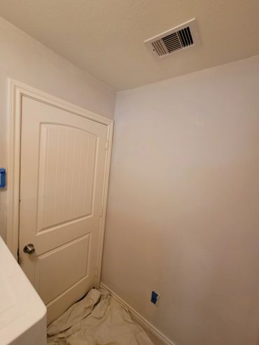 A beige room corner with a closed door and a covered floor.
