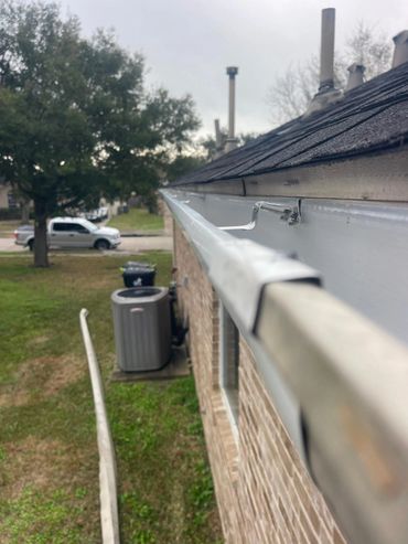 Close-up of a clean gutter on a rooftop with a ladder leaning against the house.