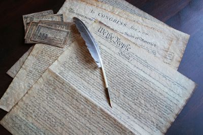 Historic American documents with a quill pen and old currency notes.