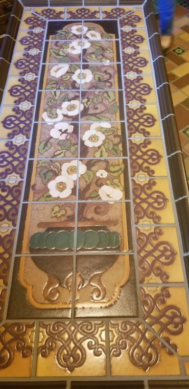 Decorative tile mural featuring a floral urn motif with handcrafted ceramic tile and ornamental Mediterranean-inspired borders.