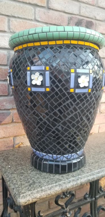 Detail of handcrafted antique tile planter featuring art deco floral tile accents and black geometric mosaic tilework.
