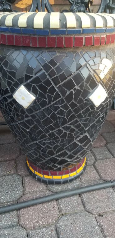 Detail of handcrafted antique tile planter featuring art deco floral tile accents and black geometric mosaic tilework.