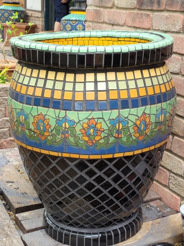 Handcrafted terracotta planter featuring antique Malibu tile with floral motifs and geometric mosaic tilework.
