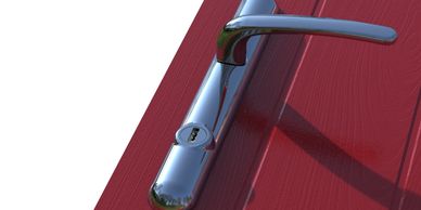 Shiny silver door handle on a red wooden door with keyhole. High-security locks with handle upgraded.