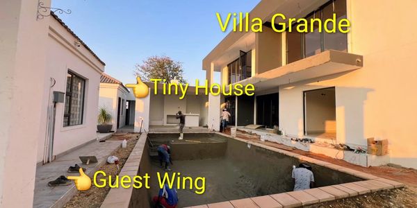 Construction workers working on a pool between Villa Grande, Tiny House, and Guest Wing.