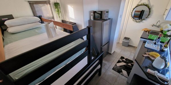 Compact studio room with bunk beds, kitchenette, and a decorative mirror on the wall.