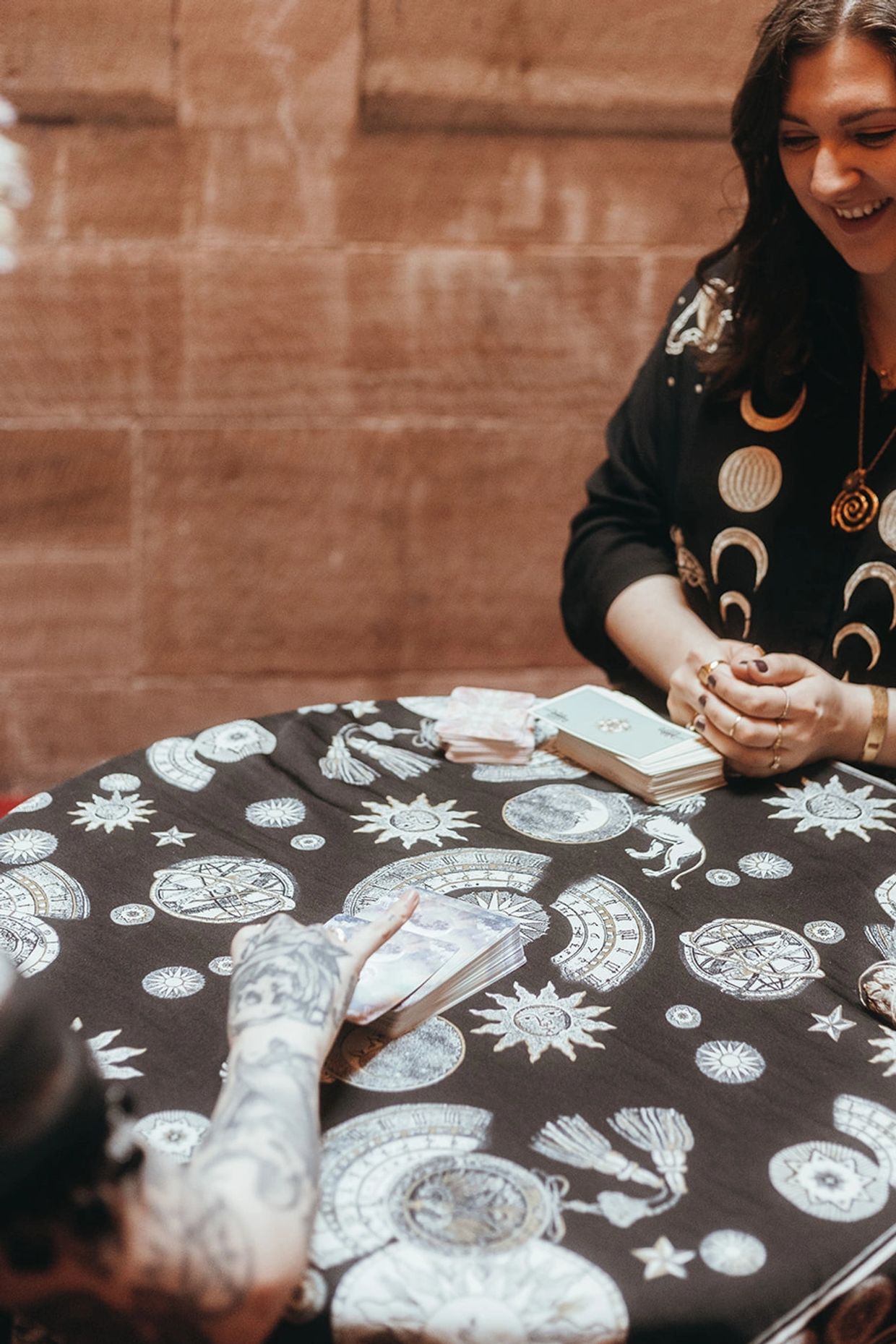 A tarot card reading session with a smiling reader and mystical decorations.