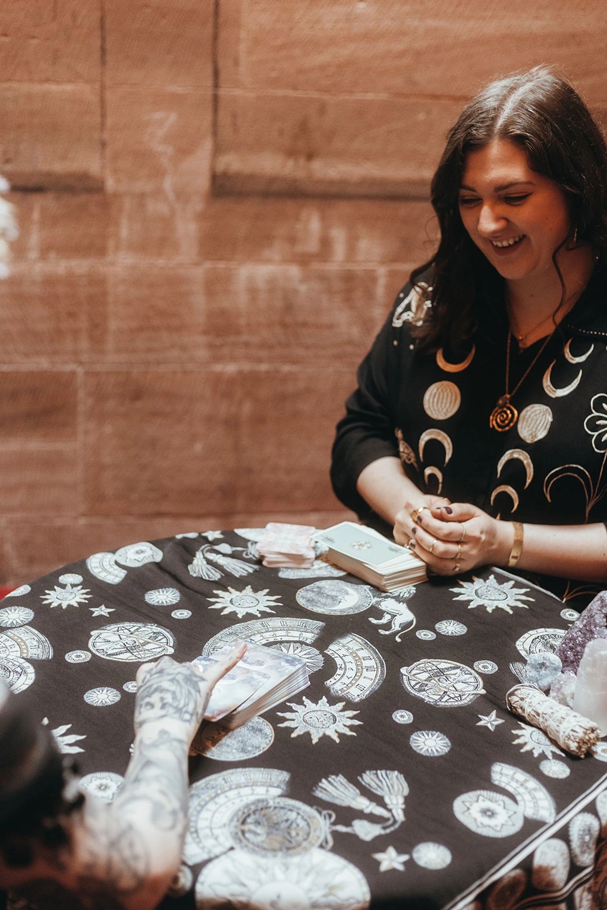 A tarot card reading session with a smiling reader and mystical decorations.