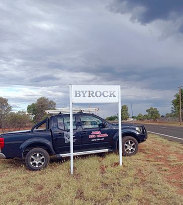 A pest control truck parked near a white sign reading BYROCK on a cloudy day.