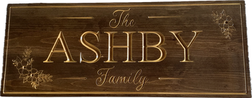Wooden sign with "The Ashby Family" engraved and floral designs.
