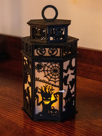 Halloween lantern with spooky designs glows on a wooden surface.