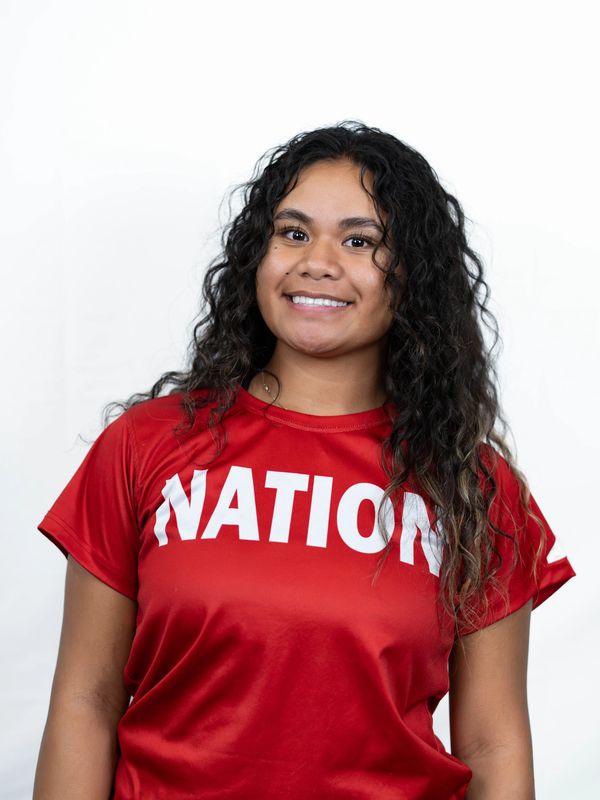 Young woman smiling, wearing a red shirt with text.