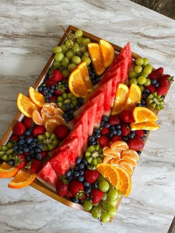 A vibrant fruit platter with watermelon, oranges, grapes, strawberries, blueberries, and kiwi.