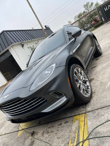 Matte black luxury sports car parked at an angle on concrete.