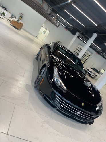 Sleek black Ferrari parked inside a modern showroom with white tiled floors.