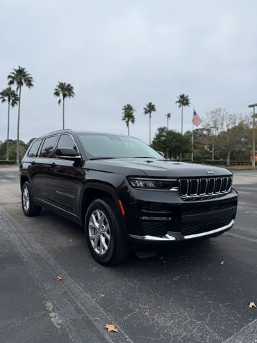 Black Jeep Grand Cherokee parked on an asphalt lot with palm trees.
