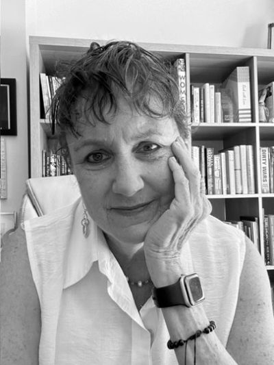 Woman resting her face on her hand, smiling gently.