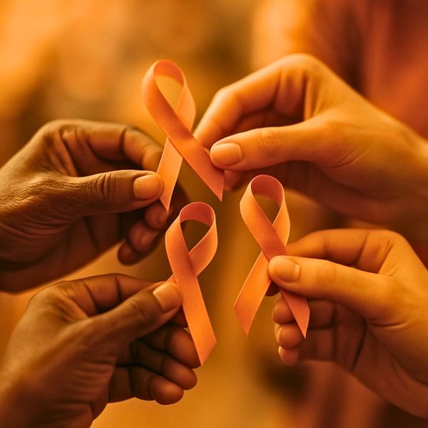 Four hands holding pink ribbons symbolizing breast cancer awareness.