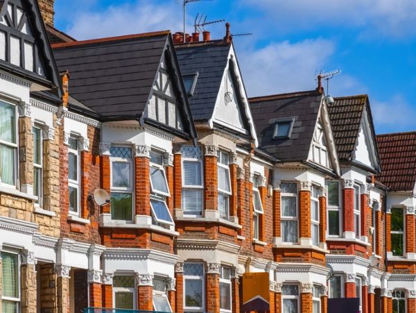 Row of traditional British terraced houses with bay windows and gabled roofs.