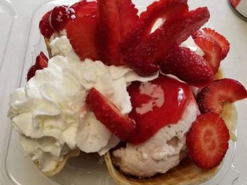 Fresh strawberries on fresh Strawberry ice cream in a delicious crunchy homemade waffle cone