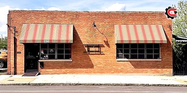 Brick building with striped awnings and large windows on a sunny day.