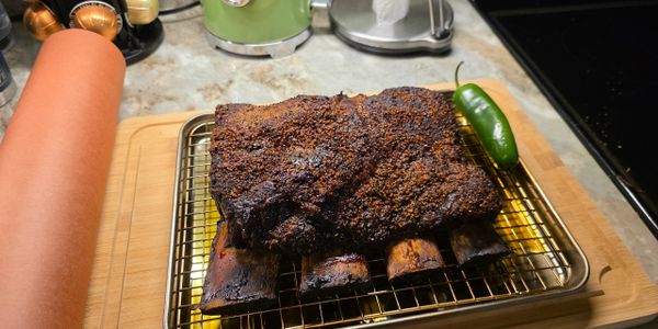 Smoked beef ribs with a jalapeño on a cooling rack.