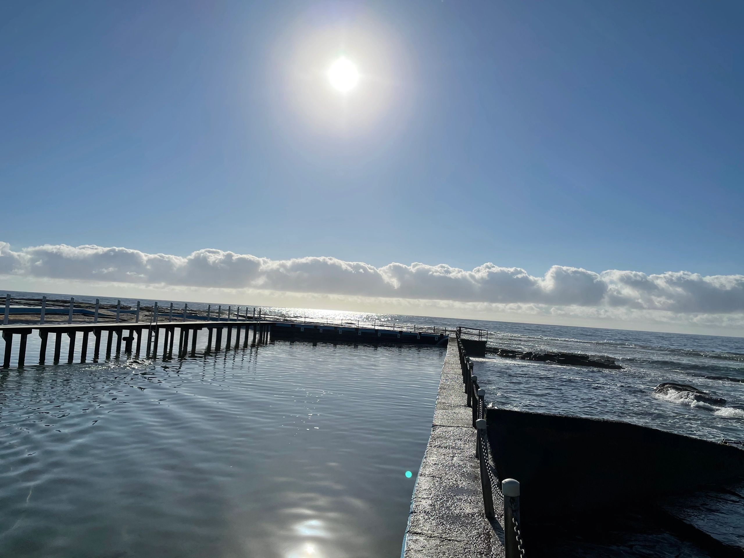 Sunny day at a peaceful waterfront with a pier and calm waters.