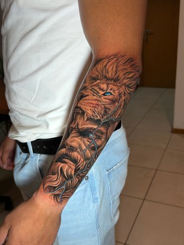 Detailed lion tattoo with a blue eye and lightning on a forearm.
