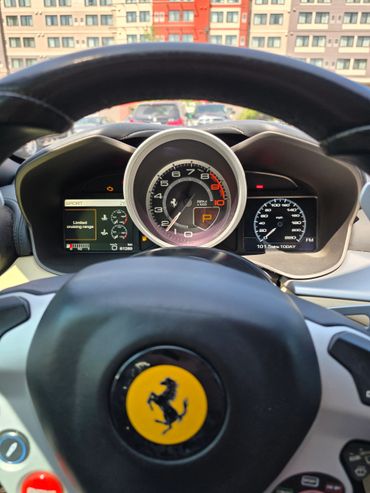 View of Ferrari FF V12 dashboard and steering wheel with RPM and speedometer.