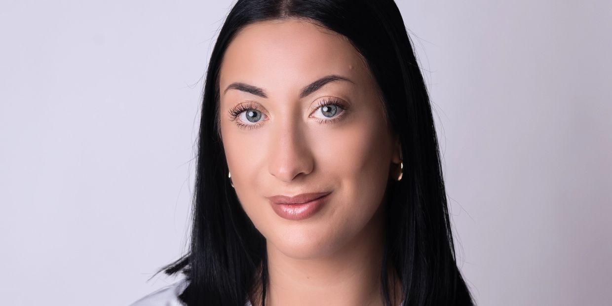Close-up portrait of a woman with black hair and blue eyes.