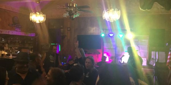 Dimly lit party with people dancing under colorful lights.