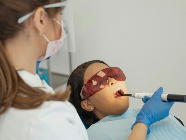 Closeup shot of dentist in protection mask working with tooth cavity and plague.
