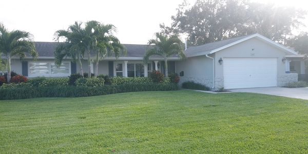 Single-story house with palm trees and a well-maintained lawn.