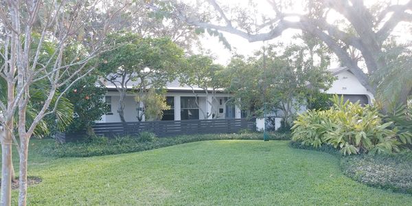 A single-story house with a lush green lawn and trees in front.