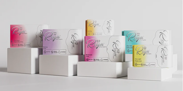 Assorted Reign sanitary napkin packages displayed on white blocks.