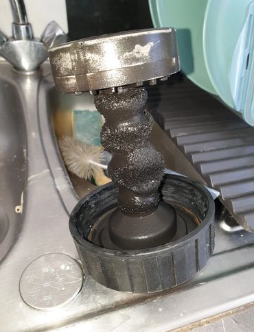 Corroded magnetic shower filter covered in iron deposits.