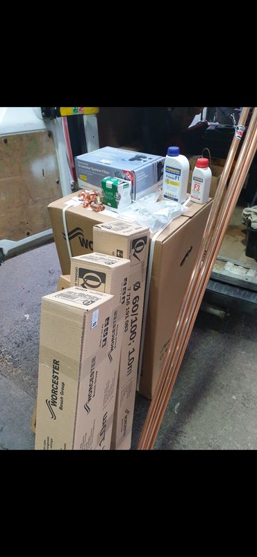Stack of plumbing supplies and copper pipes in a workshop or van.