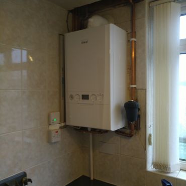 Wall-mounted boiler with connected copper pipes.