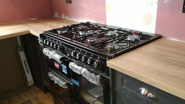 Newly installed gas stove with wooden countertops in kitchen.