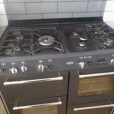 Black gas stove with multiple burners and ovens.