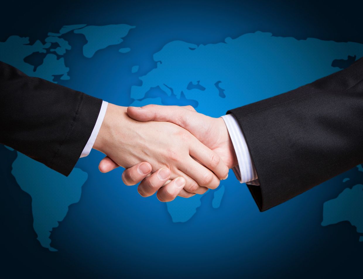 Two businesspeople shaking hands dressed in suits.