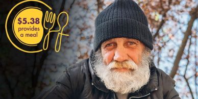 Elderly man with a beard and beanie smiling outdoors.