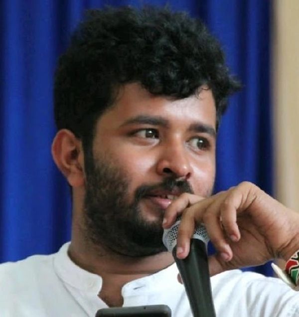 Man speaking into a microphone with a thoughtful expression.