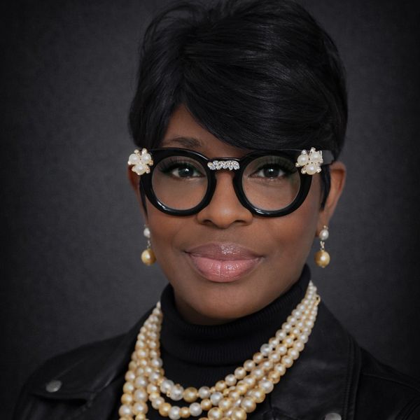 Elegant woman wearing stylish glasses and layered pearl necklaces.